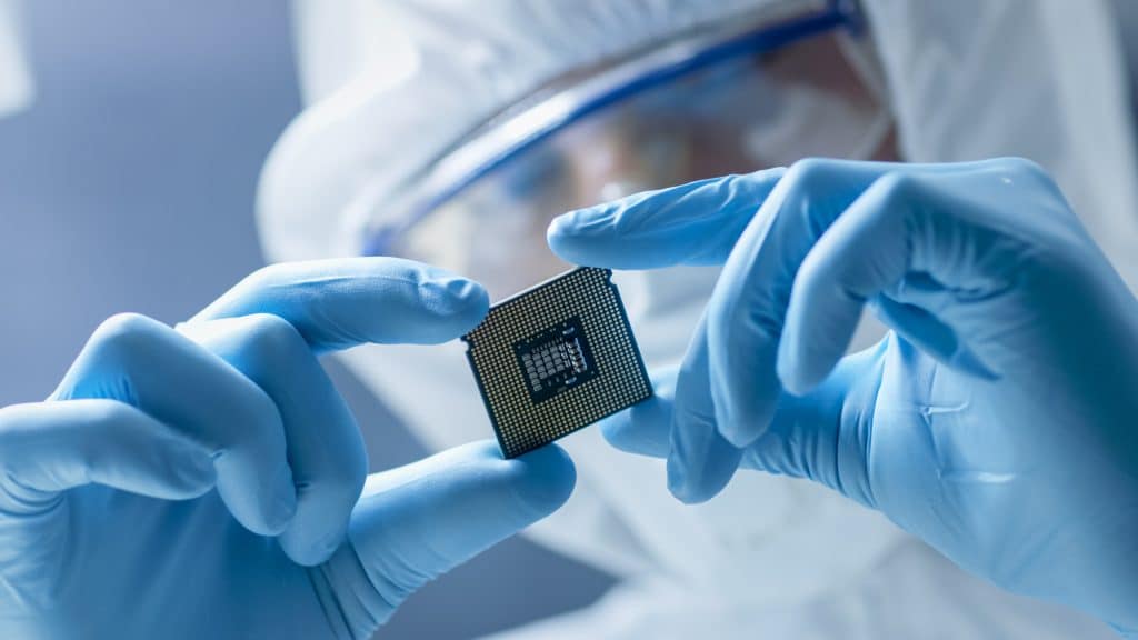 worker in protective gear examining a microchip